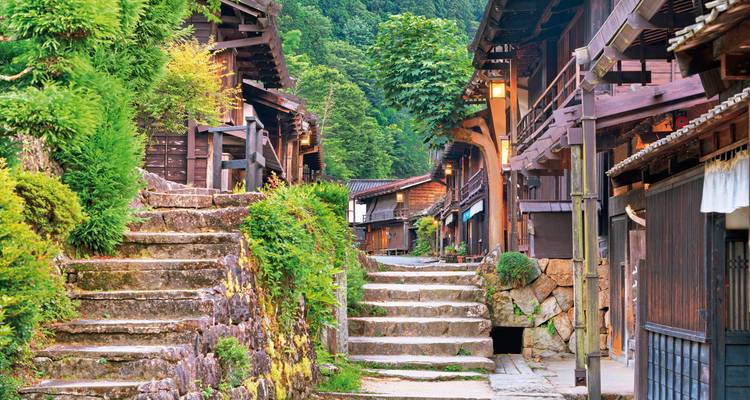 Traditional Japanese village street with lush greenery.