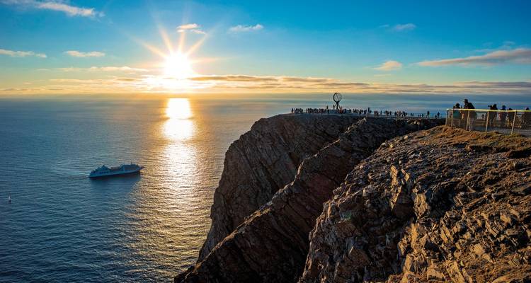 Vue de falaise avec un monument et un navire au coucher du soleil.