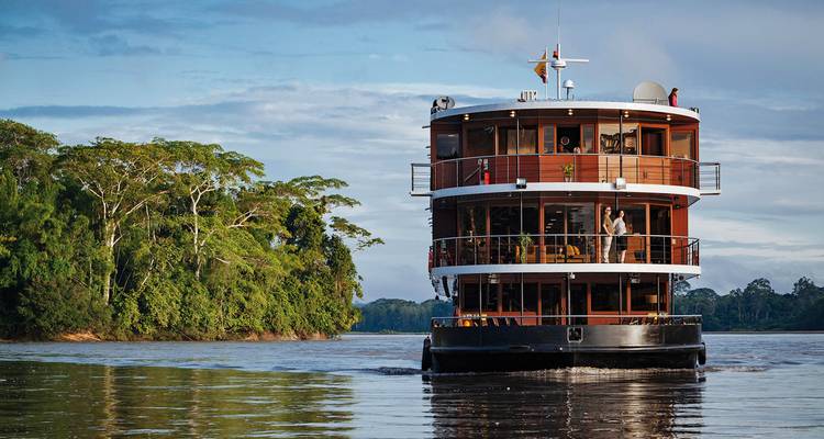 Un barco de crucero fluvial navegando por el río con exuberante vegetación alrededor.