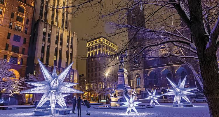 Place de la ville la nuit avec des étoiles illuminées et des bâtiments historiques.
