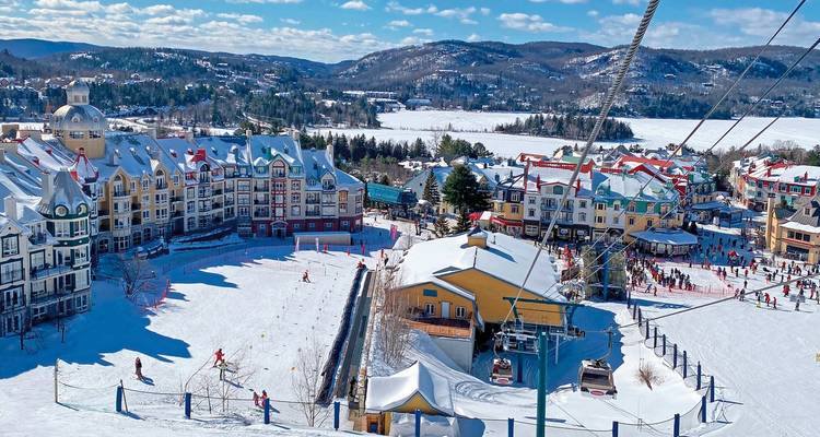Station de ski avec des bâtiments colorés et un paysage enneigé.