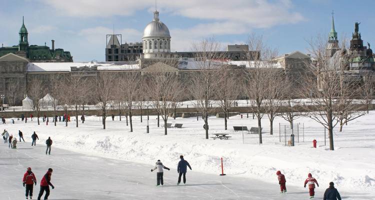 Ice skaters on a frozen lake with historical buildings.