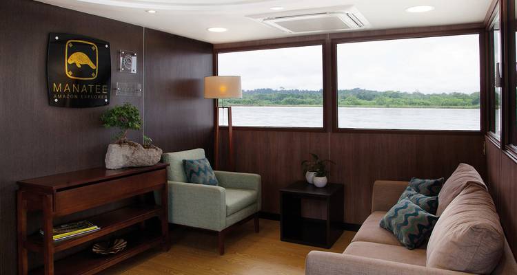 Intérieur d'un bateau de croisière avec de grandes fenêtres donnant sur un paysage fluvial.