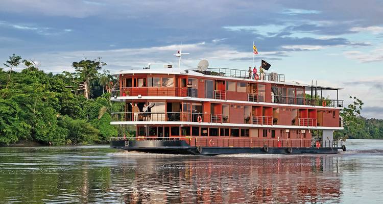 Grand navire de croisière fluviale naviguant sur l'eau avec des gens sur le pont.