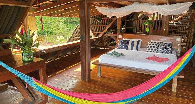 Interior of an open wooden cabin with a hammock.