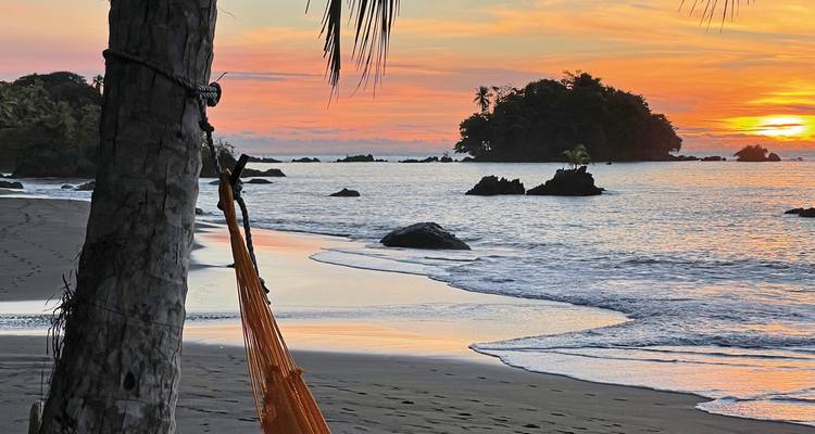 Sunset over the beach with a hammock and ocean.