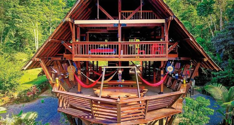 Wooden lodge with open design amidst tropical greenery.