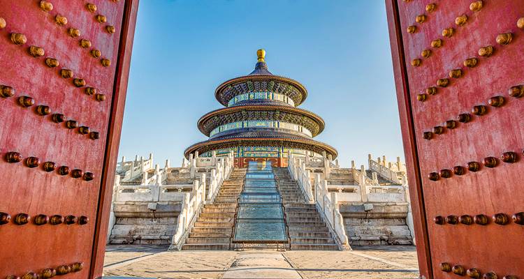 Kunstvoll verzierter Tempel, betrachtet durch große rote Türen an einem klaren Tag.