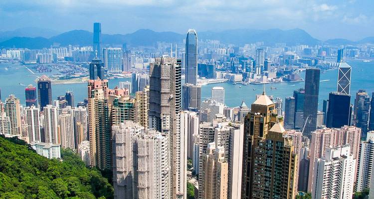 Luftaufnahme einer Stadtsilhouette mit hohen Wolkenkratzern und einem Hafen.