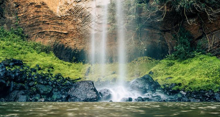 Une cascade qui dévale une paroi rocheuse dans un bassin d'eau.