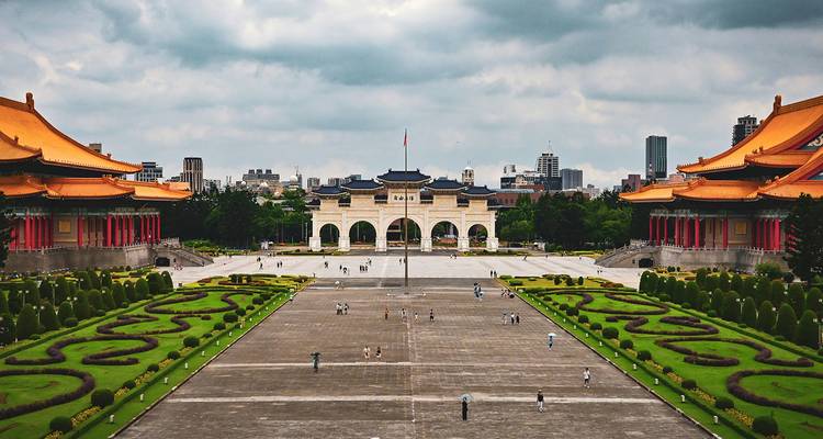 Een groot plein met traditionele architectuur en tuinen in een stedelijke omgeving.