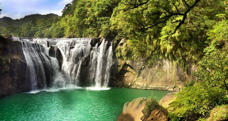 Poderosa cascada cae en cascada hacia una piscina esmeralda rodeada de exuberante bosque