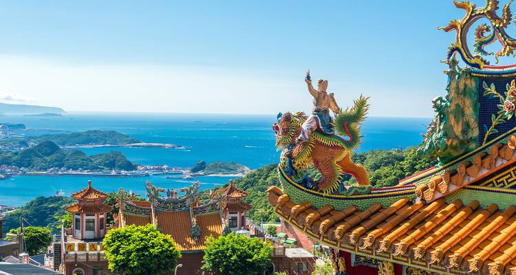 Temple orné au sommet d'une colline avec une statue de dragon colorée surplombant la côte bleue du Pacifique près de Taipei.