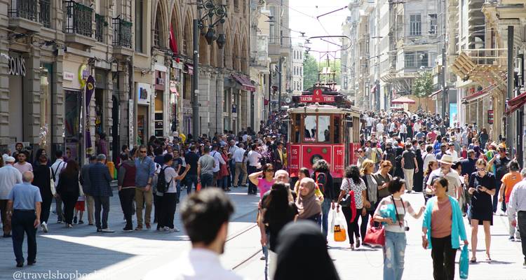 Die überfüllte Istiklal-Straße mit historischer roter Straßenbahn, die sich durch Scharen von Einkäufern und Fußgängern bewegt.