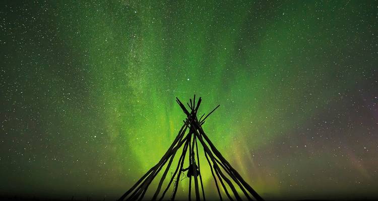 Aurora Borealis achter een structuur van houten palen.