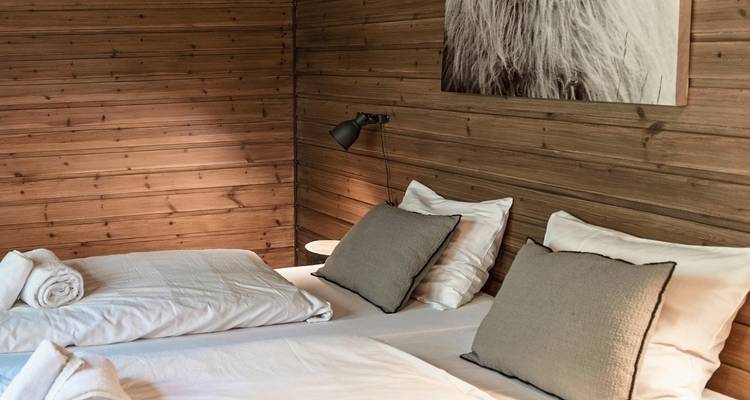 Intérieur d'une chambre de cabane en bois avec lits jumeaux.