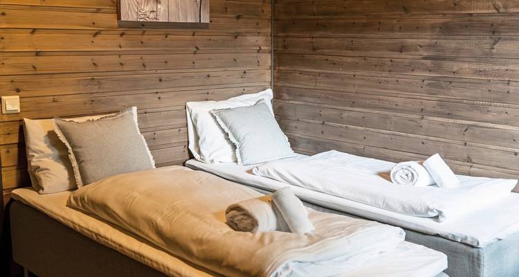 Chambre intérieure avec deux lits simples soigneusement faits et des murs en bois.