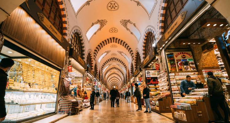 Geschäftiger überdachter Basarkorridor gesäumt von bunten Geschäften, die Gewürze, Süßwaren und Goldschmuck unter gewölbten Decken verkaufen.