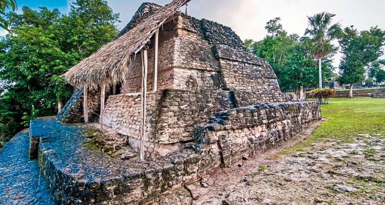 Ruinen einer Maya-Struktur mit einem Strohdach.