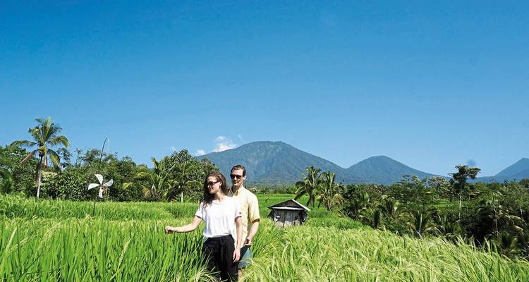 Couple se promenant dans des rizières avec des montagnes en arrière-plan.