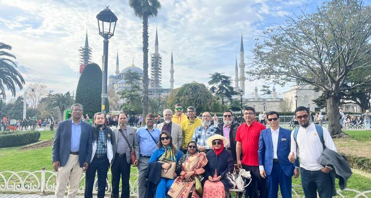 Gruppe von Reisenden steht im Park mit Kuppeln und Minaretten der Blauen Moschee im Hintergrund.
