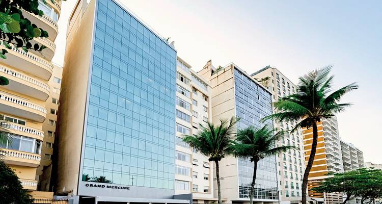 Moderne Gebäude mit Meerblick und Palmen.