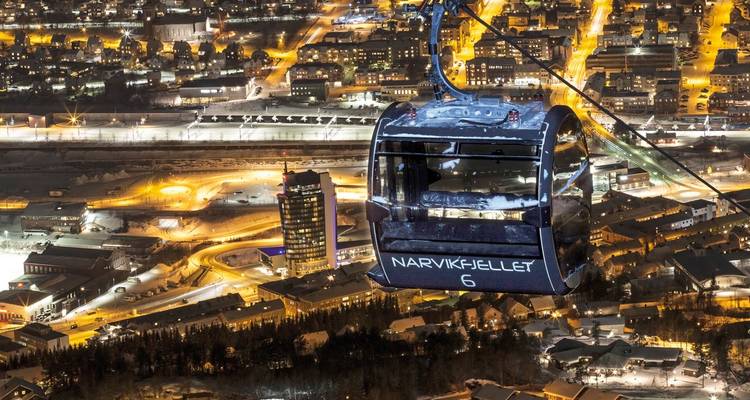 Un téléski illuminé la nuit au-dessus d'une ville avec des lumières qui brillent dans la nuit.