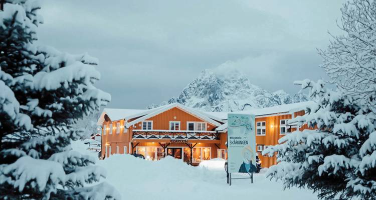 Bâtiment recouvert de neige avec un arrière-plan montagneux.