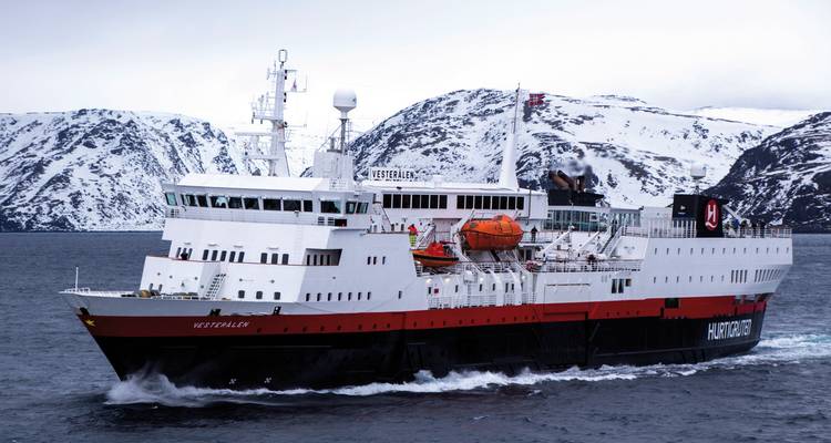Hurtigruten ship sailing through calm waters with snowy mountains.
