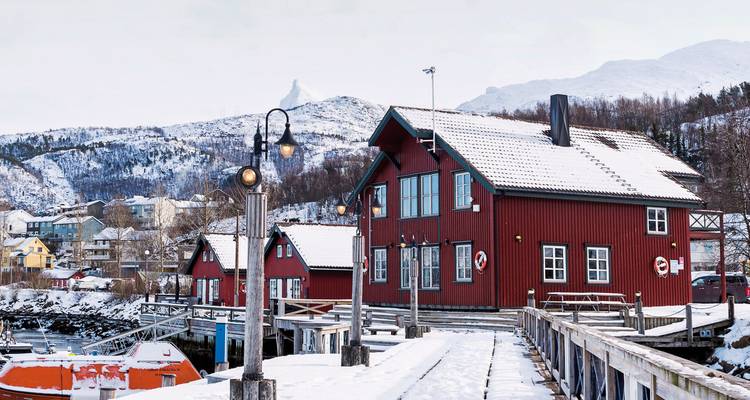 Village portuaire pittoresque couvert de neige avec des bâtiments rouges.