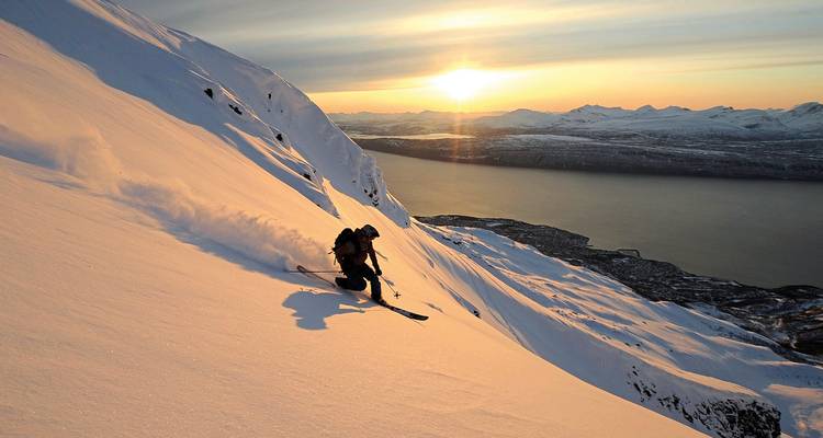 Skier au coucher du soleil sur une montagne enneigée.