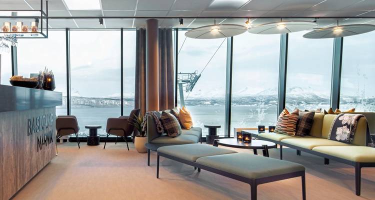Intérieur moderne avec de grandes fenêtres donnant sur des sommets enneigés.