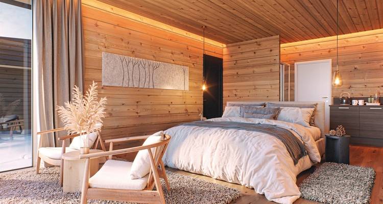 Innenraum einer gemütlichen Holzhütte mit einem großen Bett und Blick auf eine verschneite Landschaft.