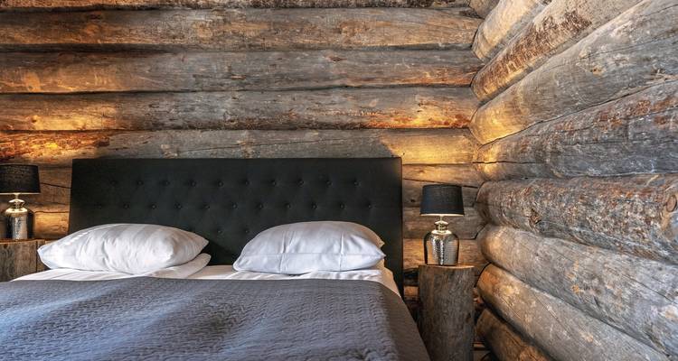 Intérieur d'une cabane en rondins avec un lit et des lampes.