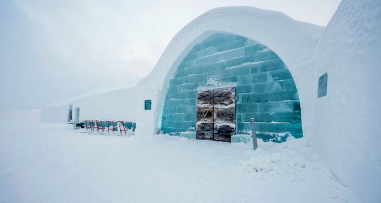 Entrance to an ice hotel with a snowy landscape.