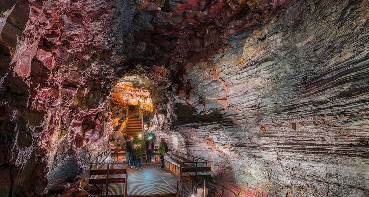 Des gens marchant à l'intérieur d'une grotte vibrante et colorée.