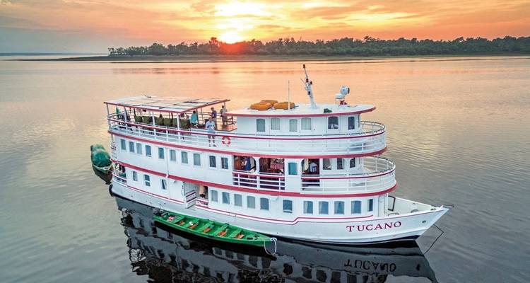 Bateau à vapeur blanc sur une rivière au coucher du soleil.
