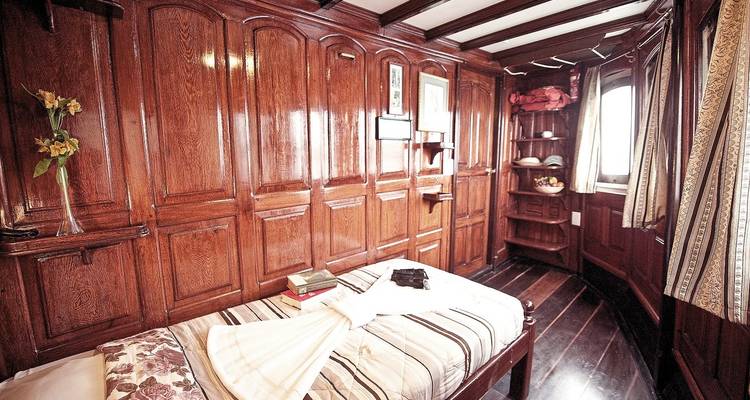 Interior de cabaña con paneles de madera con una cama individual.