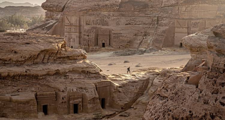 Person exploring rock carved tombs in a canyon.