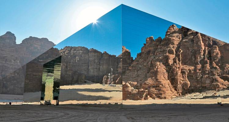 Futuristic mirrored building reflecting desert landscape.