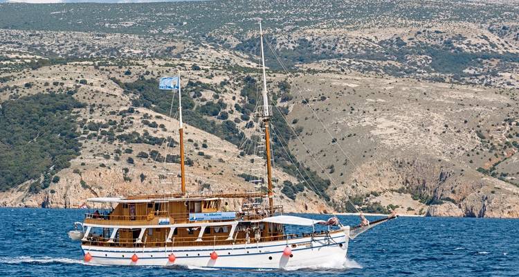 Voilier naviguant près de falaises escarpées.