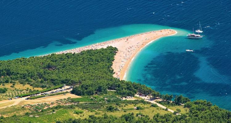 Vue aérienne panoramique de la plage de Zlatni Rat avec forêt et eau bleu clair.