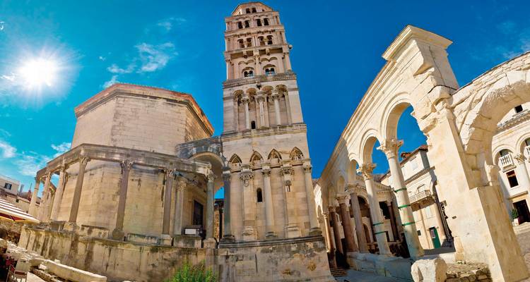 Bâtiments historiques en pierre avec une tour sous un ciel bleu clair.