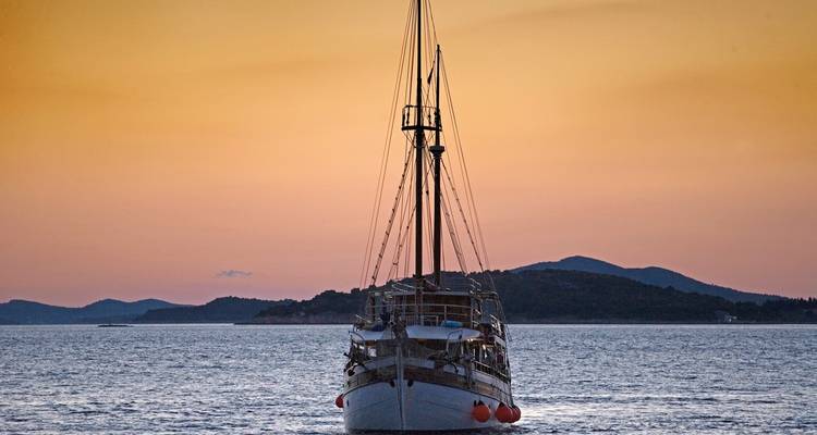 Bateau aligné avec le coucher de soleil créant une atmosphère sereine.