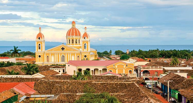 A beautiful cathedral with bright orange domes in a cityscape overlooking the sea.