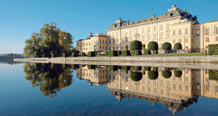 A large historic building by a calm lake.