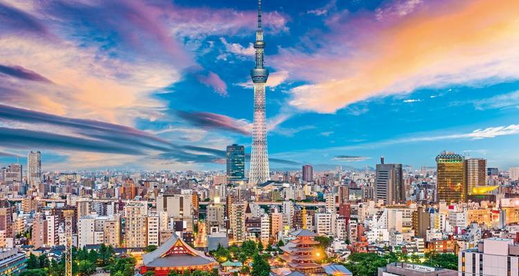 Skyline mit einem hohen Turm und farbenfrohem Himmel in der Dämmerung.