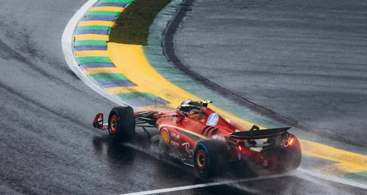 Formel-1-Autorennen auf einer regnerischen Strecke mit leuchtenden Fahrbahnmarkierungen.