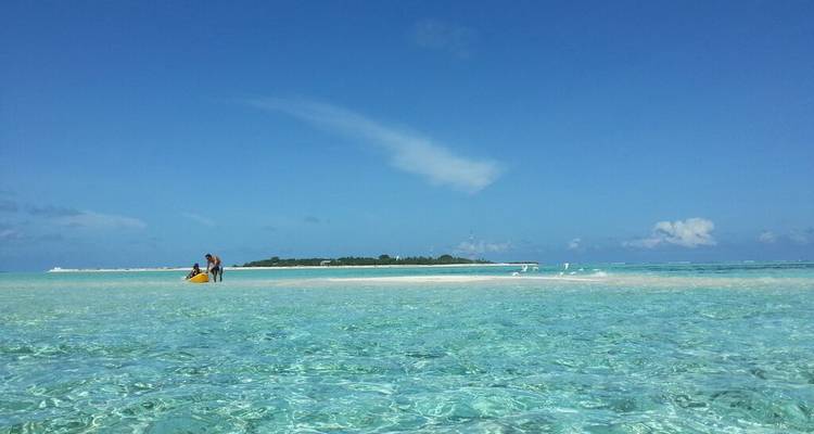 People on a sandbank surrounded by turquoise clear water.