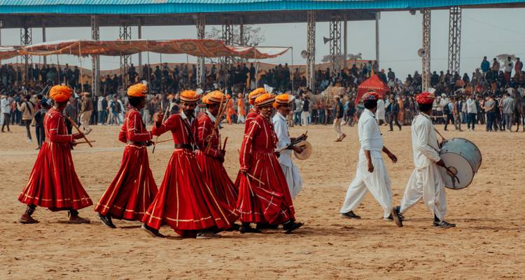 Group of people in traditional attire in a sandy arena